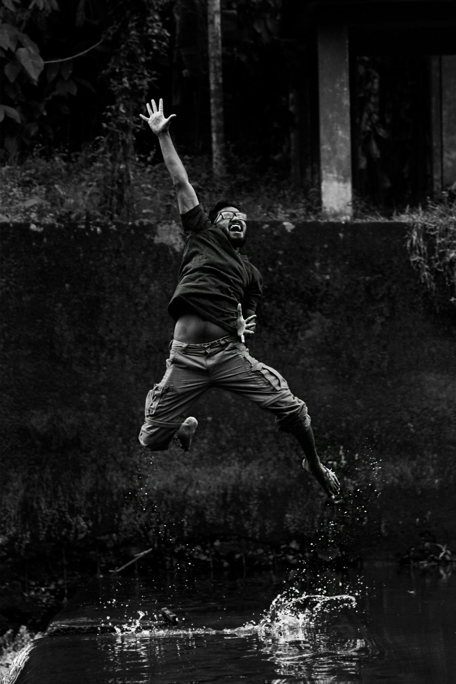 Black and white image of a man jumping with water splashes, expressing freedom.
